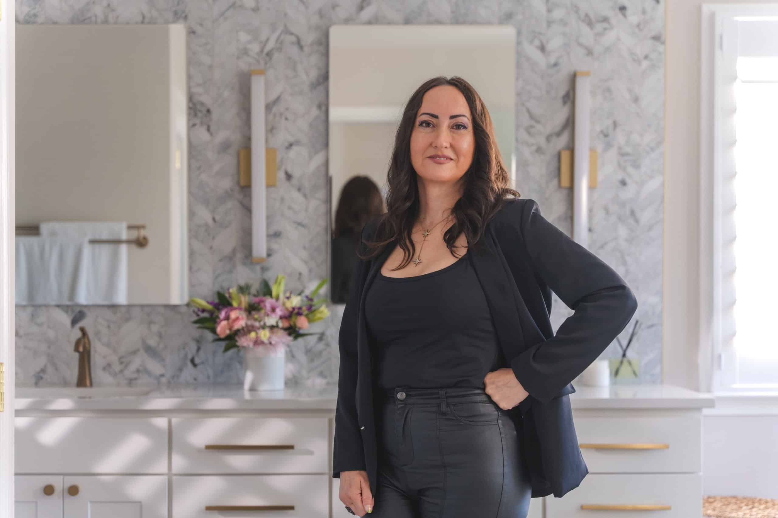 a woman standing in the bathroom in front of a mirror